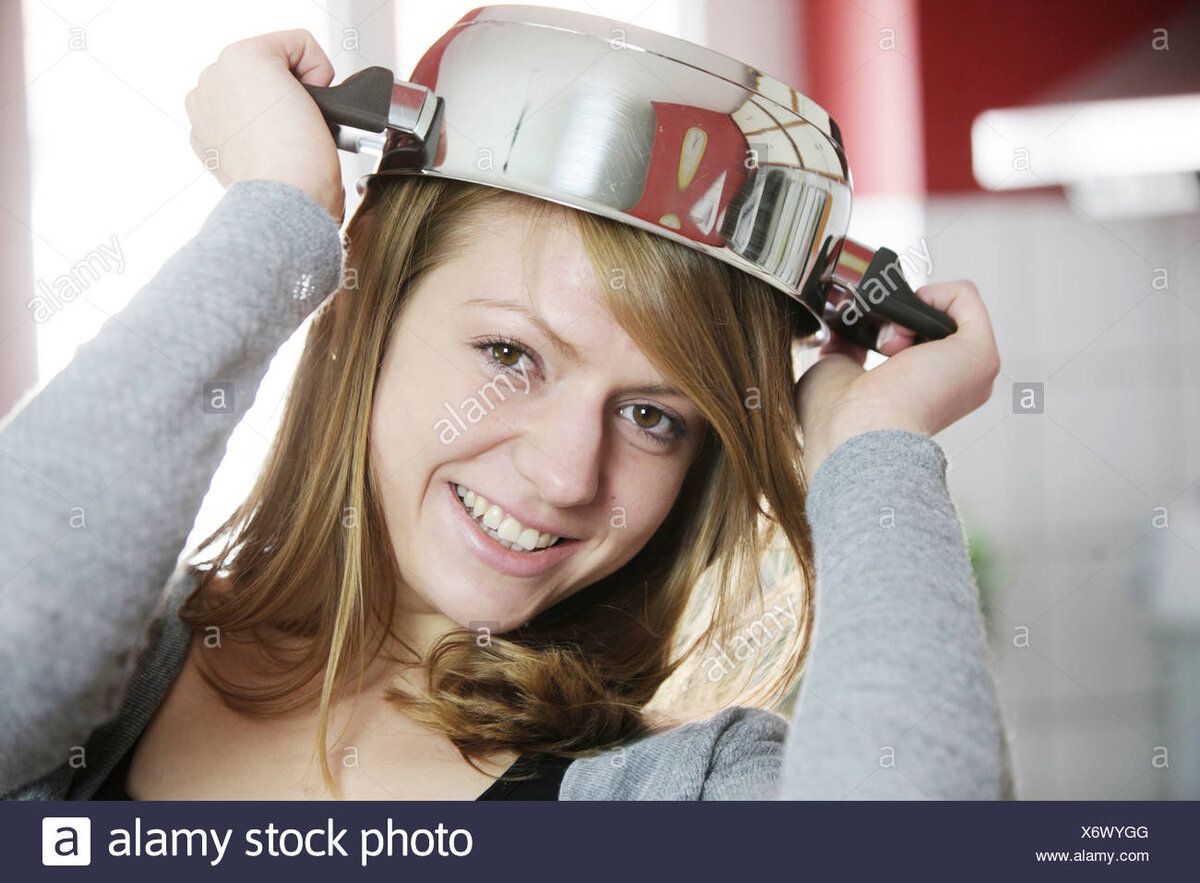 young-woman-in-the-kitchen-with-cooking-pot-as-a-hat-X6WYGG.jpg