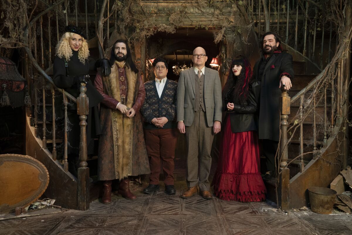 The cast of What We Do in the Shadows poses for a portrait on set.