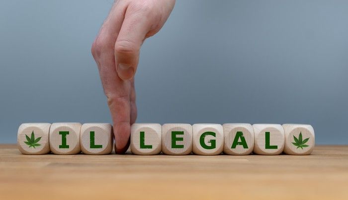 A hand splitting the word illegal on wooden blocks between il and legal.