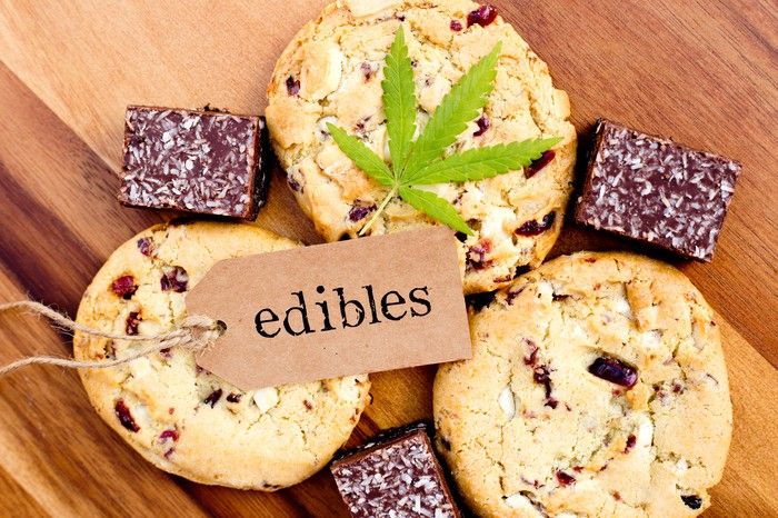 A cannabis leaf and tag that says edibles that's laying atop an assortment of cookies and brownies.