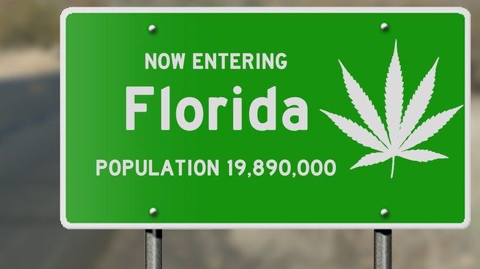 A highway sign that welcomes motorists into Florida, with a white cannabis leaf on the right portion of the sign.
