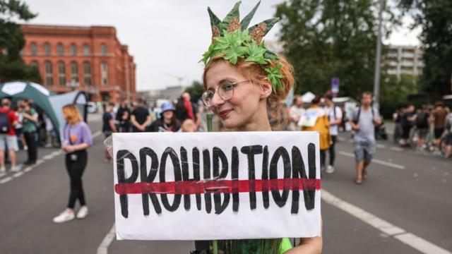 A costumed cannabis supporter holds a banner against prohibition during the annual Hemp Parade on August 12, 2023 in Berlin, Germany