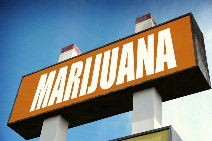 A large marijuana sign in front of a dispensary store.