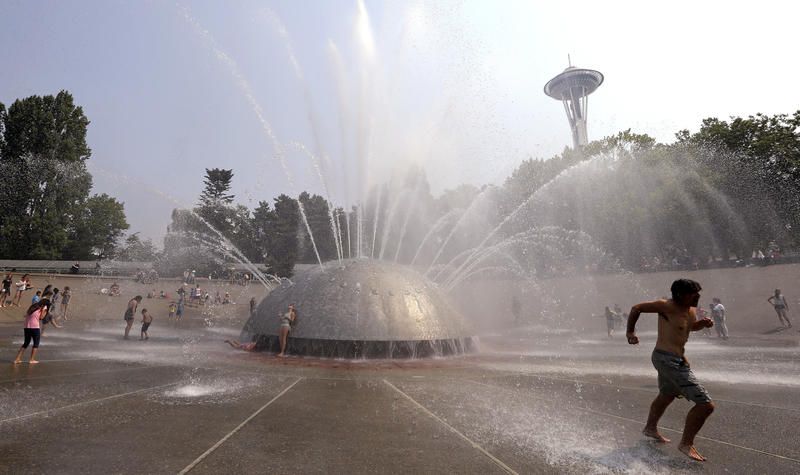 A man races away as a jet begins to spray toward him at the International Fountain at the Seattle Center during a heat wave Wednesday, Aug. 2, 2017, in Seattle.